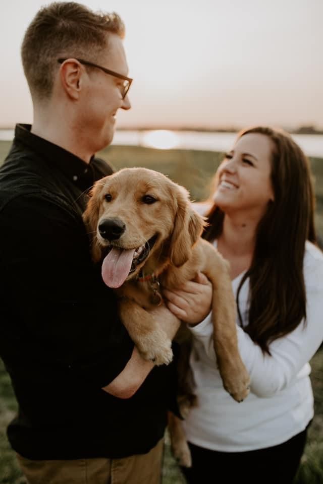 A couple holding their new golden puppy between them